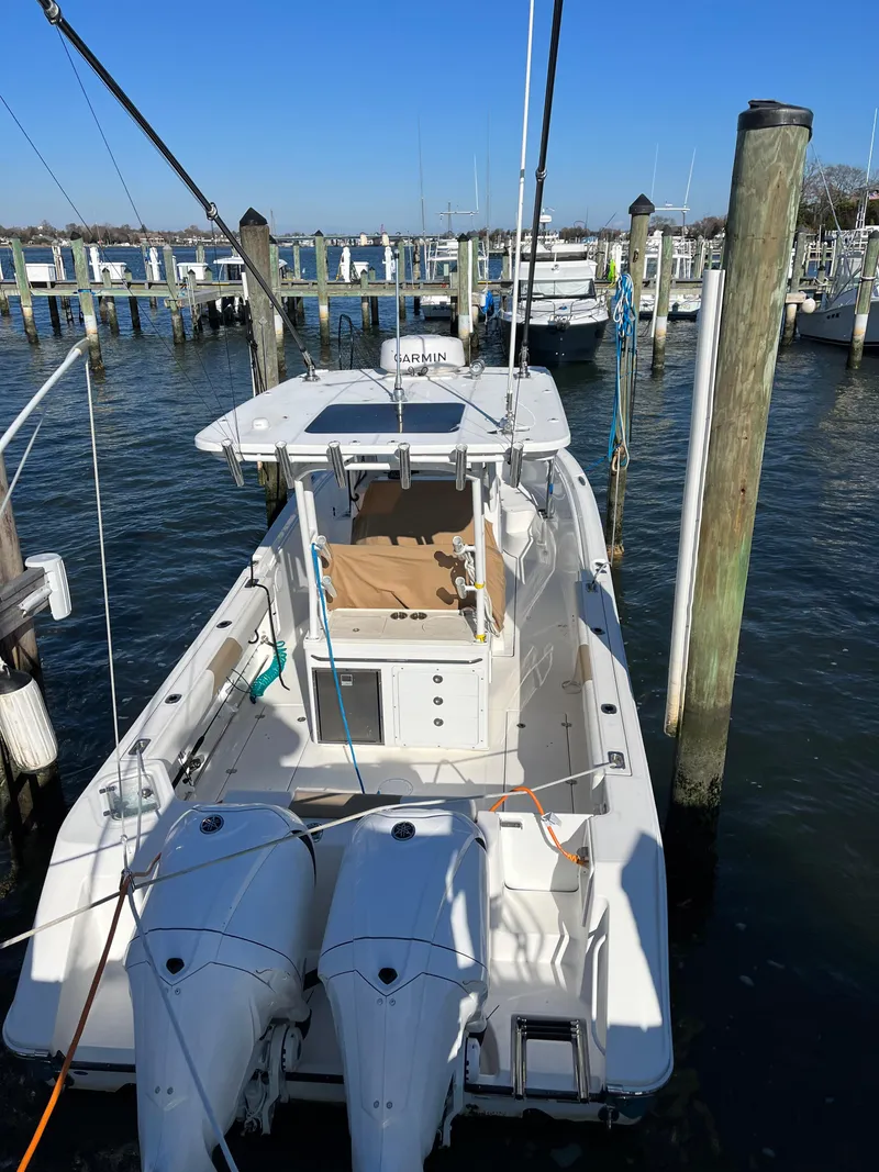 Slide: The Image of 2022 Edgewater 285CC boat docked at marina with twin engines. - 17