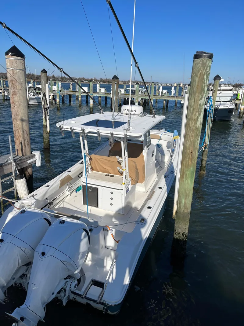Slide: The Image of 2022 Edgewater 285CC boat docked at marina with twin engines. - 18
