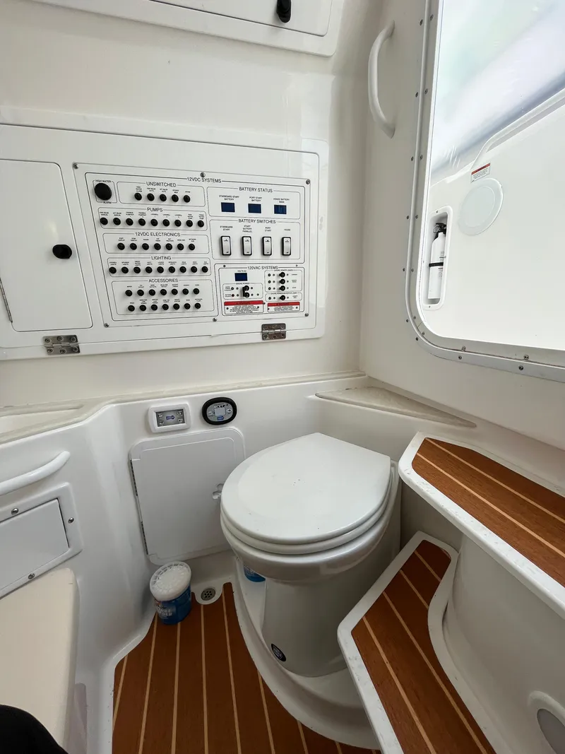 Slide: The Image of 2022 Edgewater 285CC boat interior with control panel and toilet, featuring wood accents. - 27
