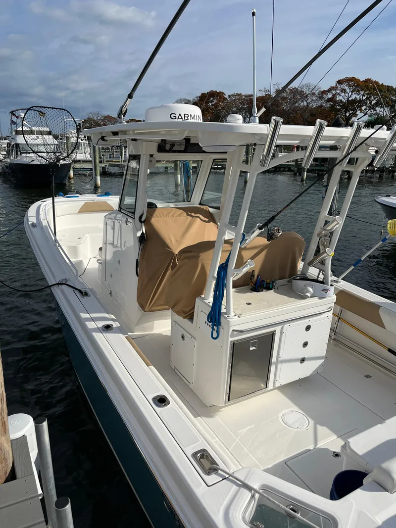 Slide: The Image of 2022 Edgewater 285CC boat docked, featuring fishing equipment and a covered console. - 3