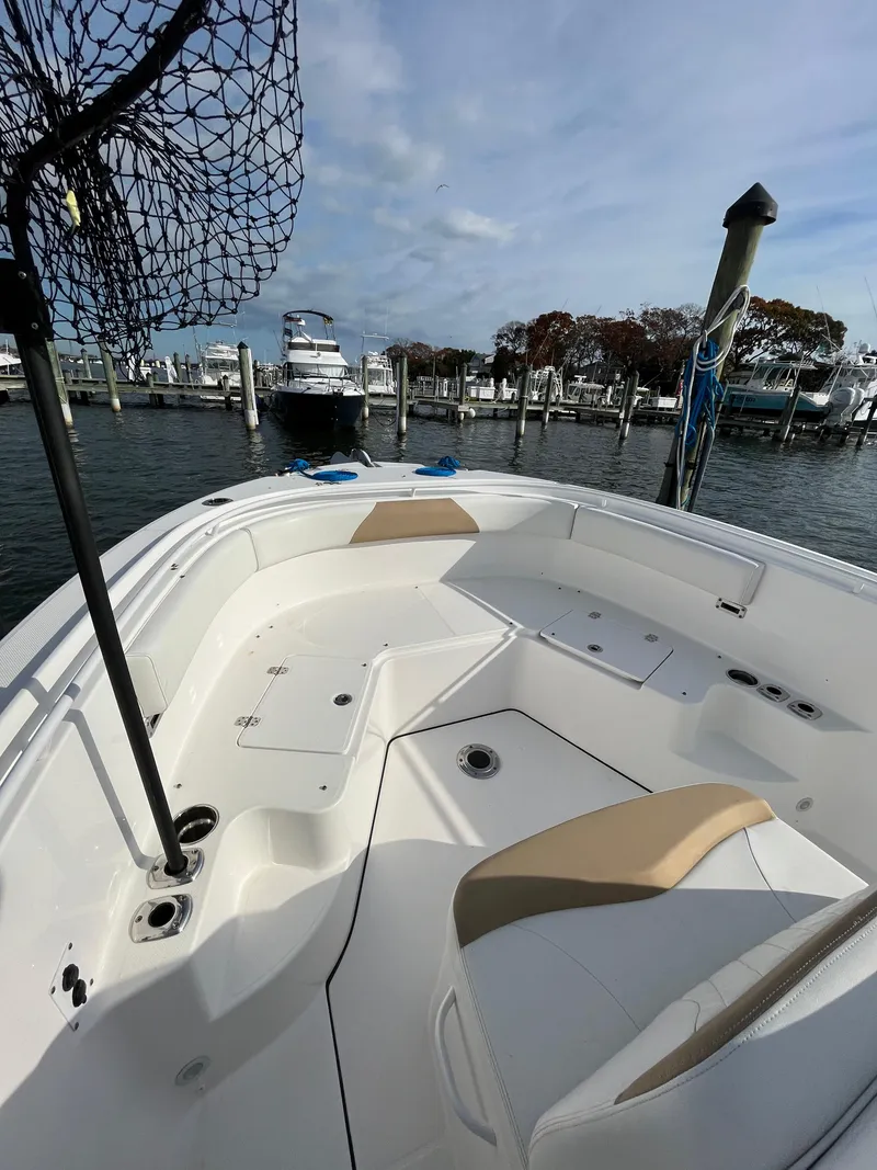 Slide: The Image of 2022 Edgewater 285CC boat docked at marina, featuring spacious seating and fishing equipment. - 4