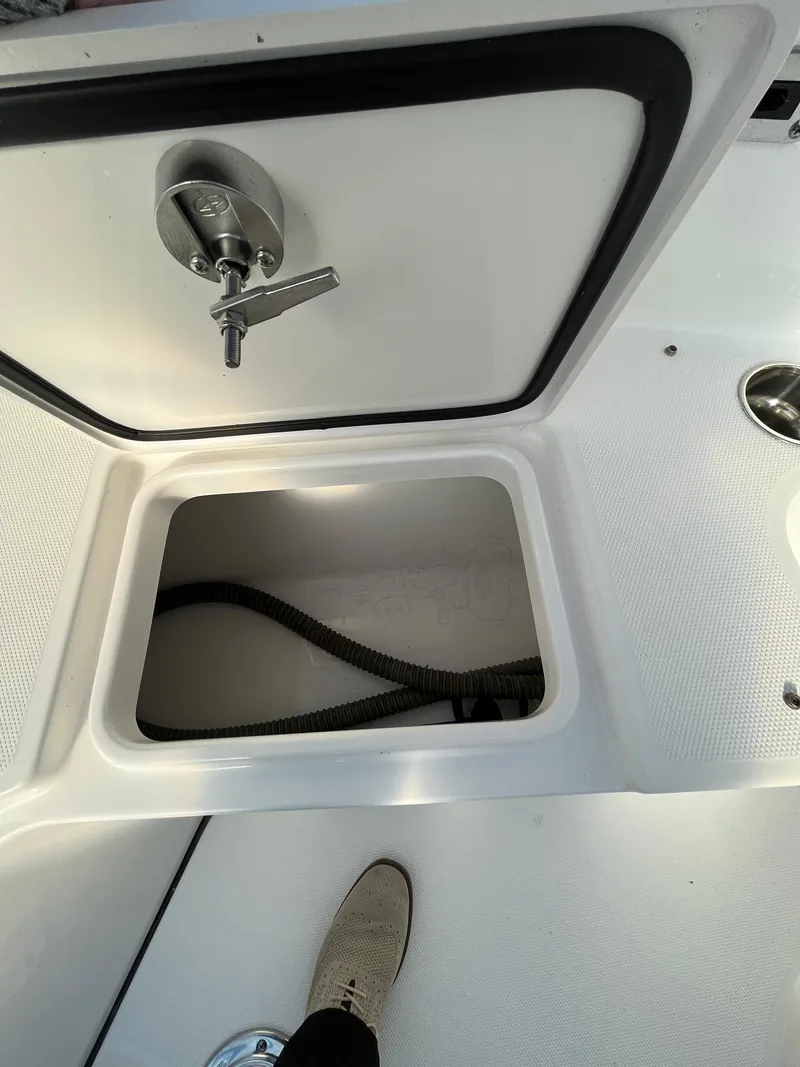 Slide: The Image of 2022 Edgewater 285CC boat storage compartment with open hatch and visible hose. - 41