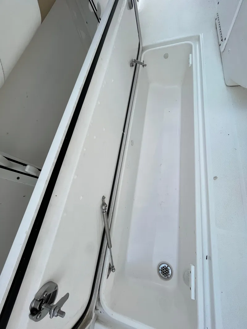 Slide: The Image of 2022 Edgewater 285CC boat storage compartment with drain, open and empty. - 42