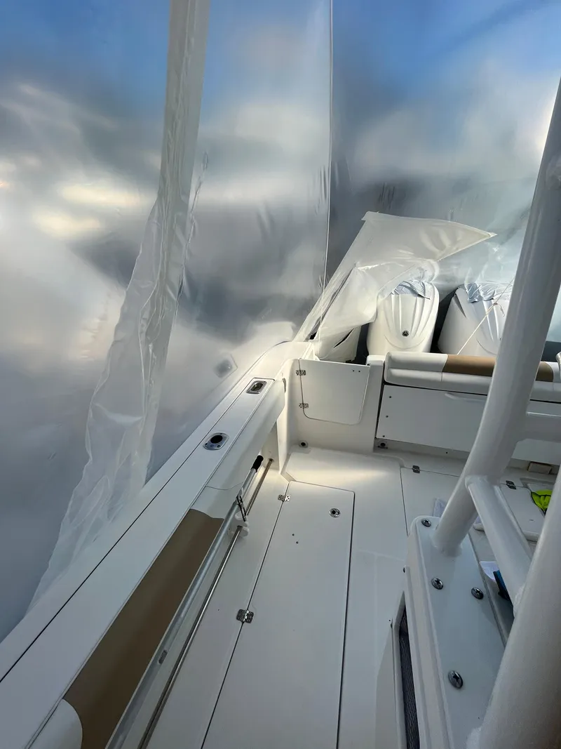 Slide: The Image of 2022 Edgewater 285CC boat interior with white seating and protective covering. - 46