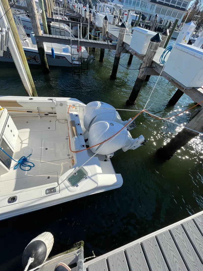 Slide: The Image of 2022 Edgewater 285CC boat docked at marina with twin engines. - 6