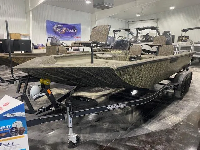 Slide: The Image of 2025 SeaArk Shadow 20 boat on trailer in showroom, camo design, indoor display. - 2