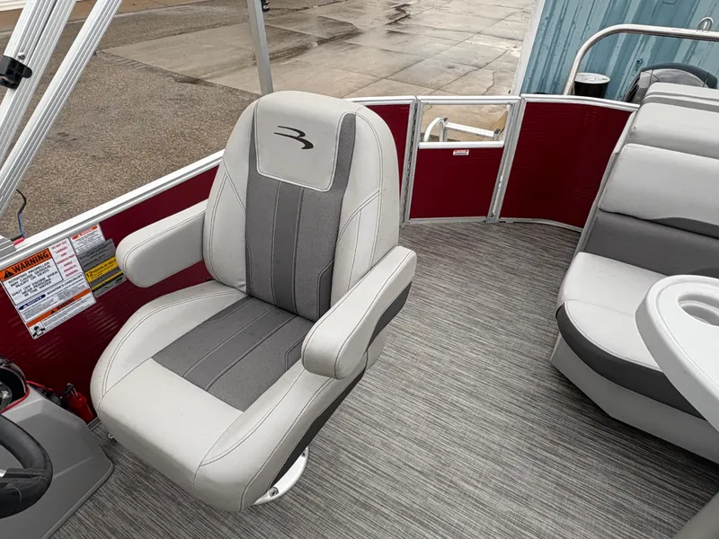 Slide: The Image of 2020 Bennington 22 SLX boat interior with gray captain's chair and red accents. - 23