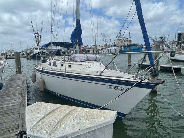 Slide: The Image of 1986 O'Day Masthead Sloop docked in a marina, under a cloudy sky. - 0