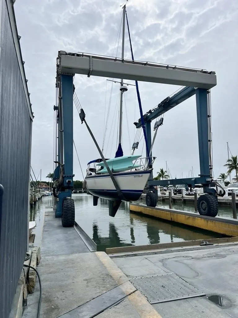 Slide: The Image of 1986 O'Day Masthead Sloop sailboat being lifted at a marina dock. - 7