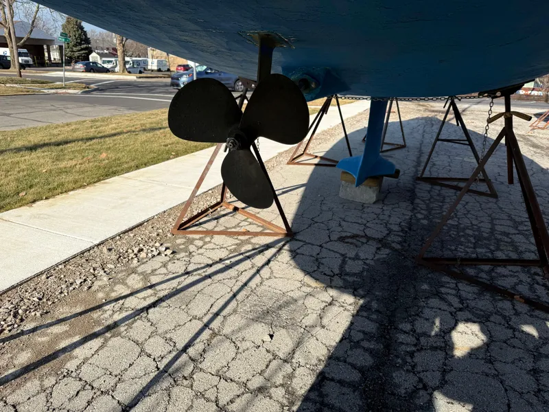 Slide: The Image of 2007 Hunter 33 sailboat on stands, showing propeller and keel on cracked pavement. - 31