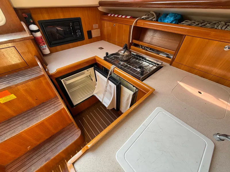 Slide: The Image of 2007 Hunter 33 yacht kitchen with stove, fridge, and microwave in wooden interior. - 4