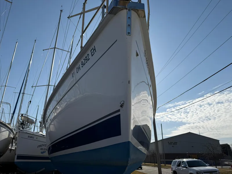 Slide: The Image of 2007 Hunter 33 sailboat on land, clear sky, parked vehicles nearby. - 42