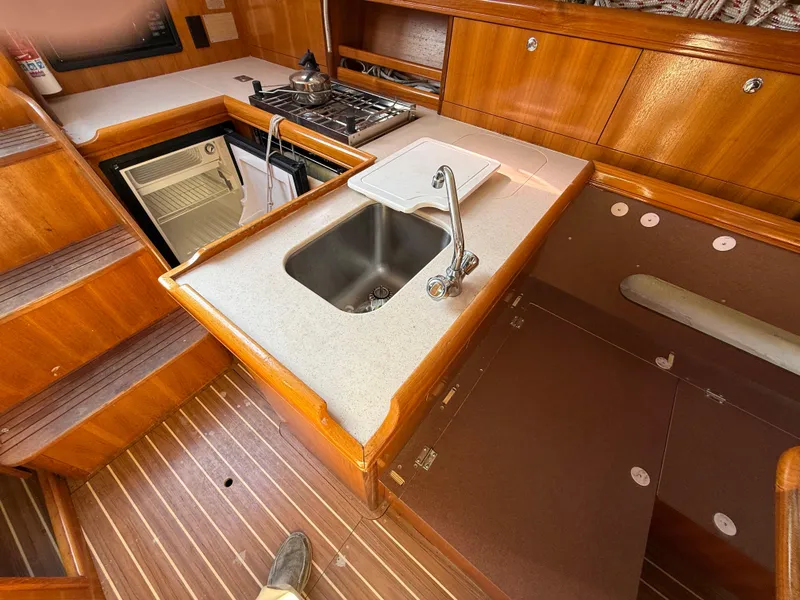 Slide: The Image of 2007 Hunter 33 yacht kitchen with sink, stove, and wooden cabinetry. - 5