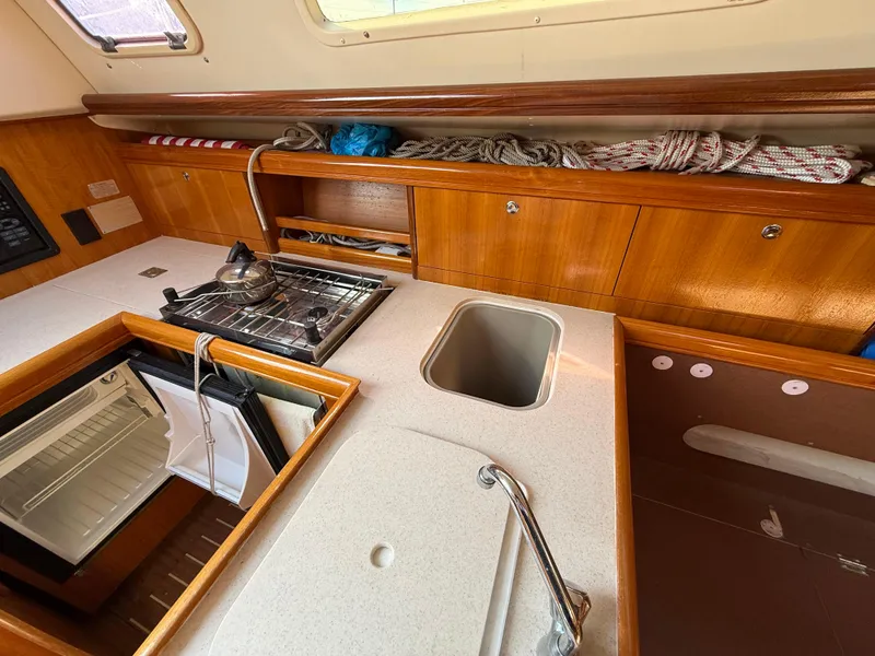 Slide: The Image of 2007 Hunter 33 yacht kitchen with stove, sink, and fridge in wooden cabinetry. - 6