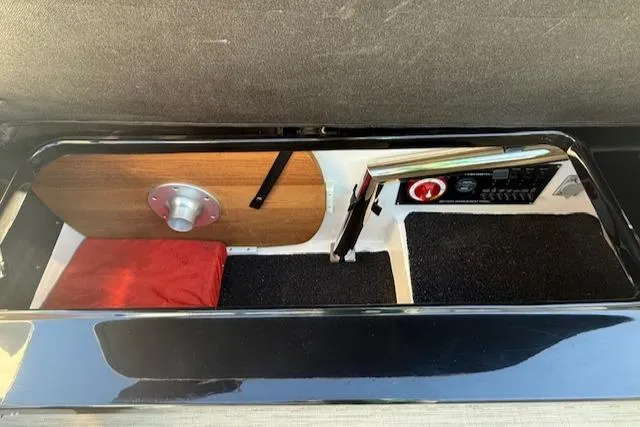 Slide: The Image of Storage compartment in a 2016 Regal 2800 Bowrider boat, featuring a red cushion and control panel. - 7