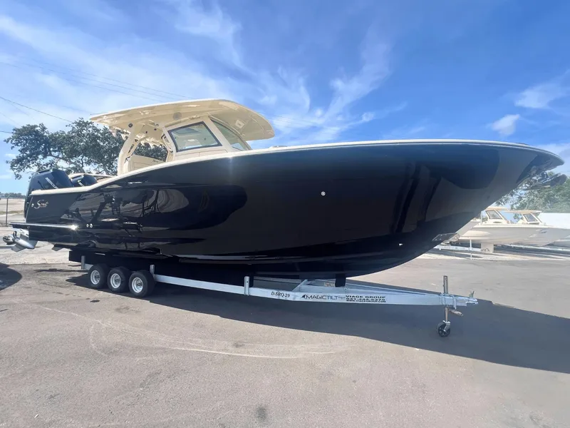 The Image of 2025 Scout 330 LXF boat on trailer under clear blue sky. - 0
