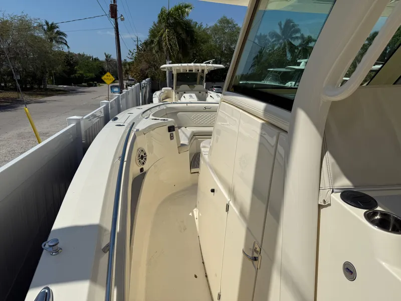 Slide: The Image of 2025 Scout 330 LXF boat, sleek design, docked near a tropical road. - 14