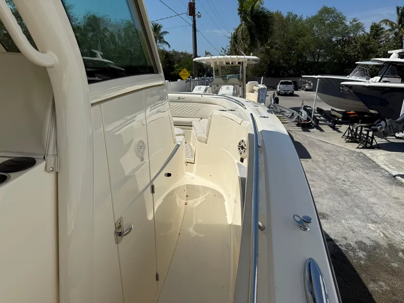 Slide: The Image of 2025 Scout 330 LXF boat, sleek design, docked outdoors, sunny day. - 15