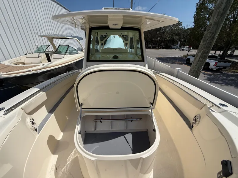 Slide: The Image of 2025 Scout 330 LXF boat with open storage compartment, docked outdoors. - 19