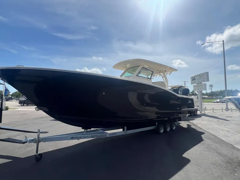 Slide: The Image of 2025 Scout 330 LXF boat on trailer under clear blue sky. - 2