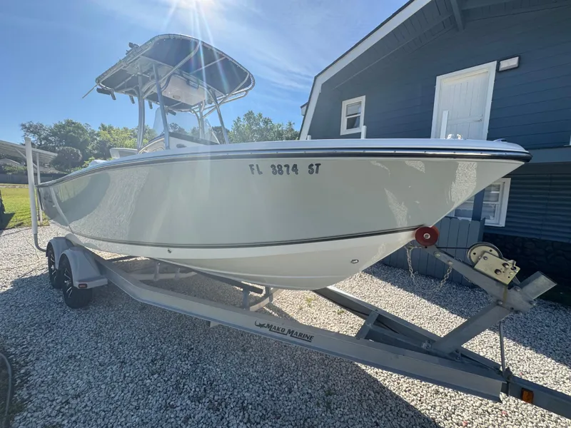 Slide: The Image of 2019 Mako 214C boat on trailer, parked beside a blue house under sunny sky. - 22