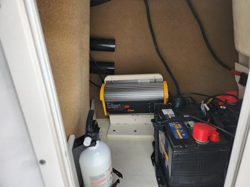 Slide: The Image of 2017 Chaparral 21 H2O Ski & Fish OB battery compartment with charger and fire extinguisher. - 17