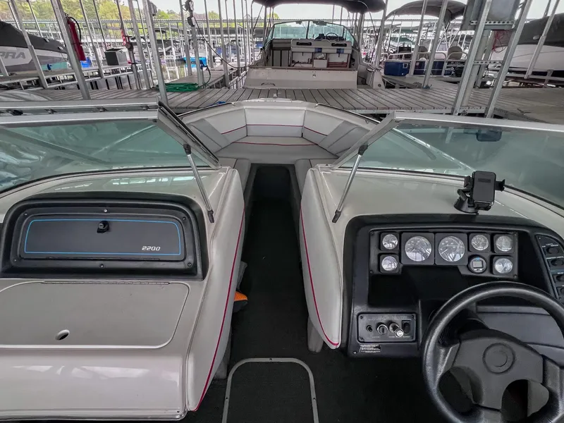 Slide: The Image of 1993 Chaparral 2200 SL boat interior with dashboard and seating, docked in a marina. - 25