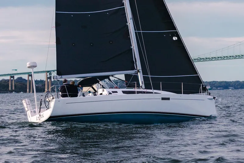 Slide: The Image of 2026 J Boats J/36 sailing on open water with black sails and bridge in background. - 6