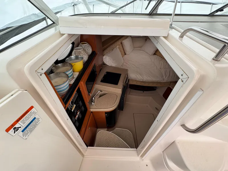 Slide: The Image of 2006 Wellcraft 290 Coastal cabin interior with kitchenette and cozy sleeping area. - 12