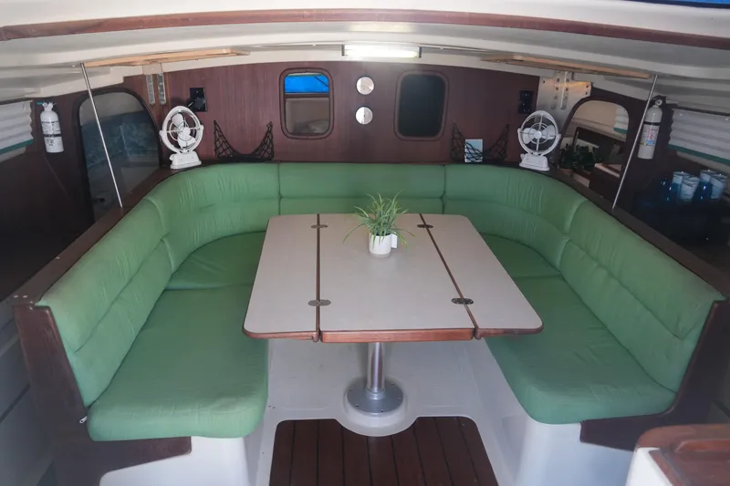 Slide: The Image of Interior of 1997 Gemini 105M catamaran with green cushioned seating and table. - 14