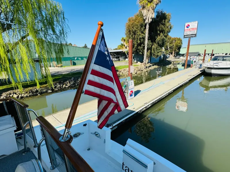 Slide: The Image of 1991 Ocean Alexander 440 Sundeck CPMY docked with American flag, sunny marina view. - 25