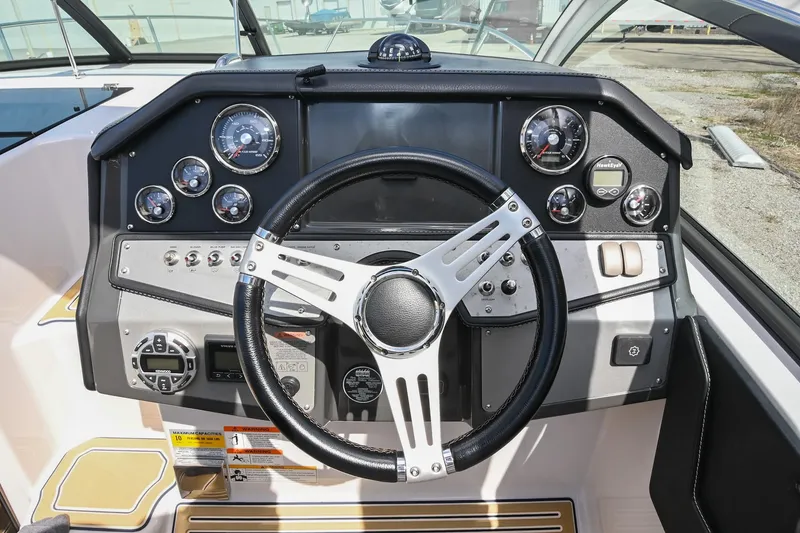 Slide: The Image of 2014 Four Winns V275 boat dashboard with steering wheel and control gauges. - 24