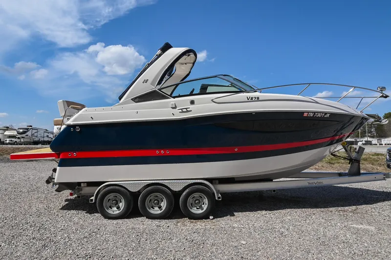 Slide: The Image of 2014 Four Winns V275 boat on trailer, blue and white design, parked outdoors. - 6