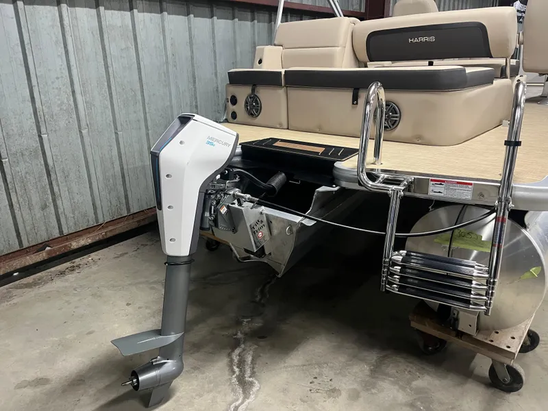 Slide: The Image of 2025 Harris Cruiser 210 pontoon boat with modern outboard motor in a storage area. - 4