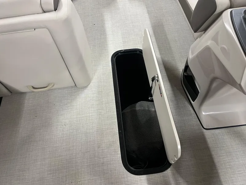 Slide: The Image of Harris Sunliner 230 boat interior storage compartment, 2025 model, open hatch on carpeted floor. - 3