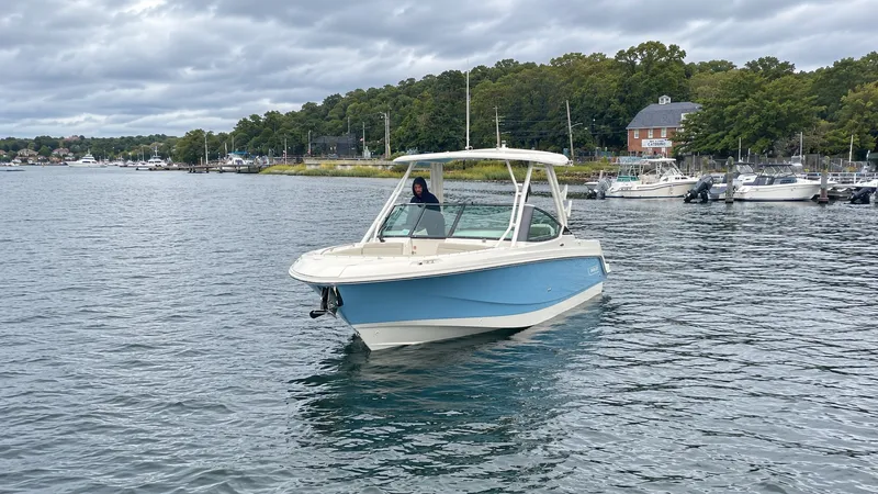 Slide: The Image of A 2026 Boston Whaler 240 Vantage on calm water, surrounded by trees and other boats. - 38