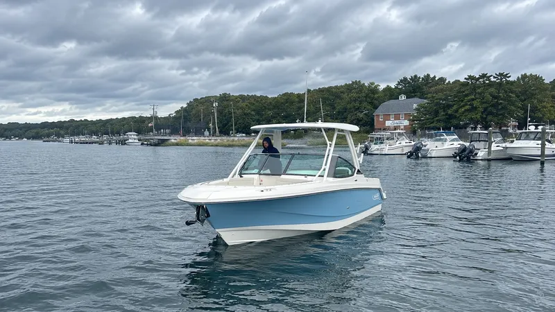 Slide: The Image of A 2026 Boston Whaler 240 Vantage on calm water. Boats and trees are visible in the background. - 37
