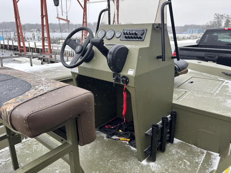 Slide: The Image of 2025 Crestliner 1660 Retriever FCC boat console with steering wheel and controls, docked in snowy setting. - 6