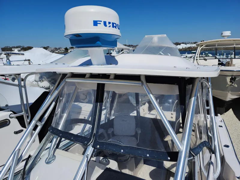 Slide: The Image of 2006 Grady-White Journey 258 boat with radar, docked in a marina under clear blue skies. - 6