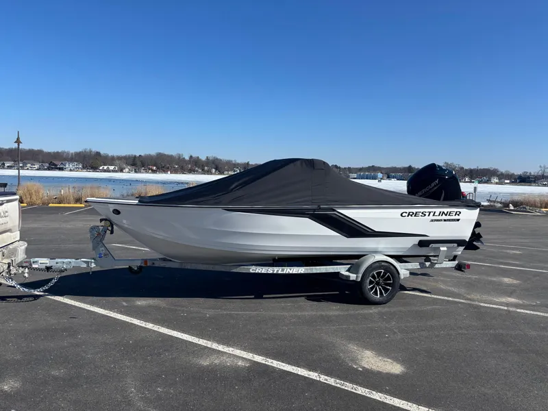 Slide: The Image of 2025 Crestliner 1750 Hawk boat on trailer, covered, parked near a lake. - 6