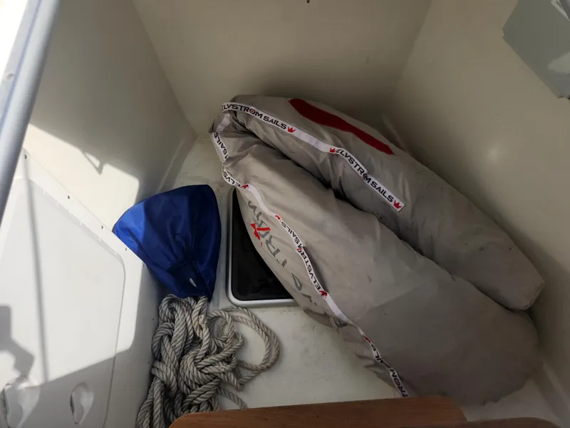 Slide: The Image of Storage compartment on 2023 Hallberg-Rassy 57 yacht with sail, rope, and blue cover. - 17