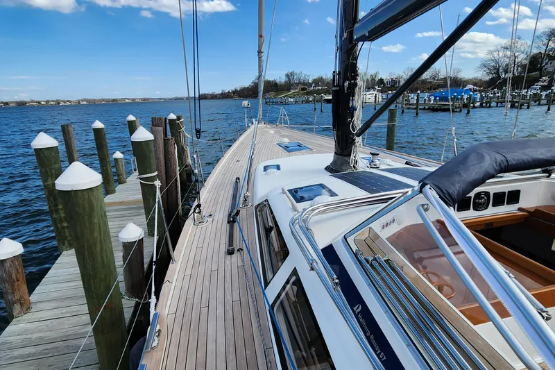 Slide: The Image of 2023 Hallberg-Rassy 57 yacht docked by a serene waterfront. - 20