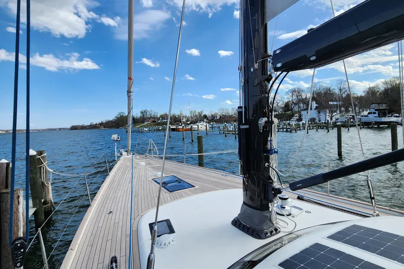 Slide: The Image of 2023 Hallberg-Rassy 57 yacht docked, showcasing sleek deck and mast under blue sky. - 21