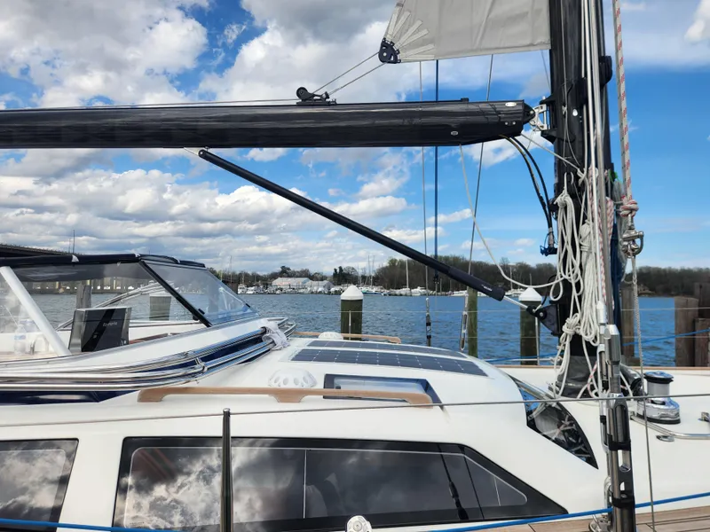 Slide: The Image of 2023 Hallberg-Rassy 57 yacht docked, showcasing sleek design and modern rigging against a scenic waterfront. - 26