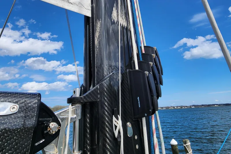 Slide: The Image of 2023 Hallberg-Rassy 57 sailboat mast with rigging against blue sky and water backdrop. - 32