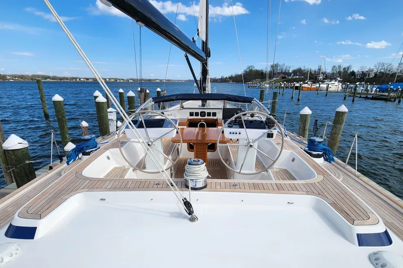 Slide: The Image of 2023 Hallberg-Rassy 57 yacht docked, showcasing dual steering wheels and teak deck. - 38