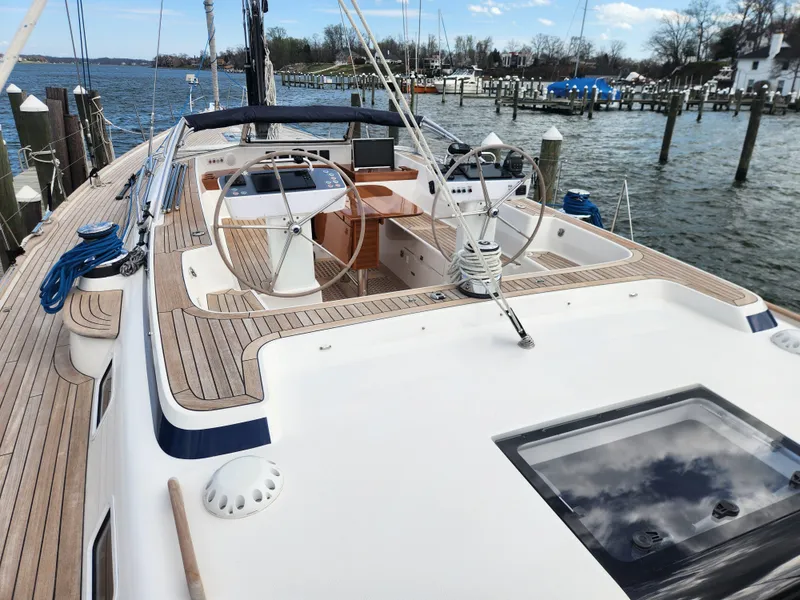 Slide: The Image of 2023 Hallberg-Rassy 57 yacht with dual steering wheels, docked at a marina. - 39