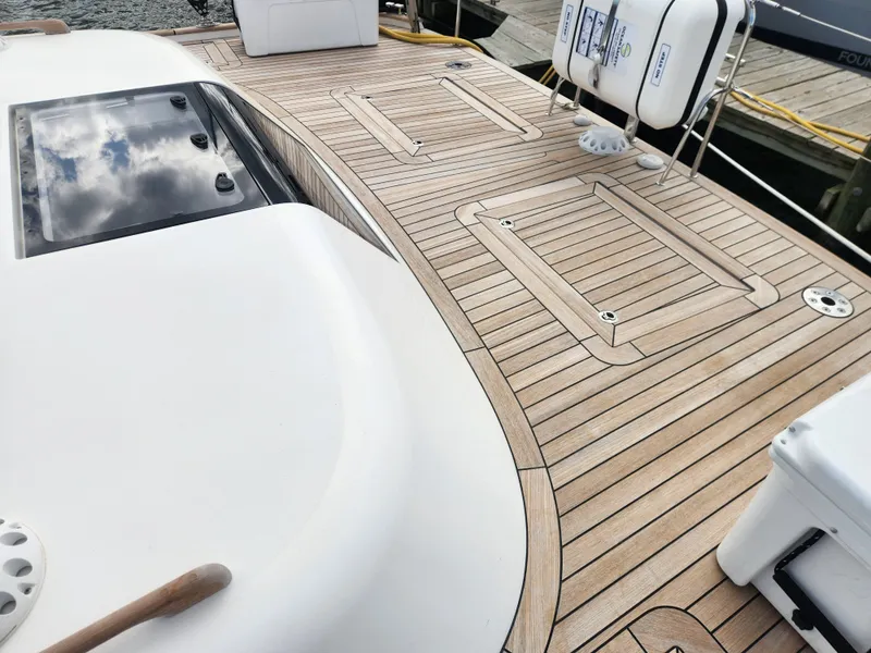 Slide: The Image of 2023 Hallberg-Rassy 57 yacht deck with teak wood finish and safety equipment. - 43