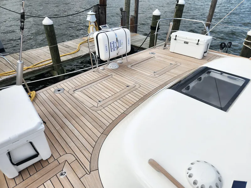 Slide: The Image of 2023 Hallberg-Rassy 57 yacht deck with wooden finish, docked at a marina. - 44