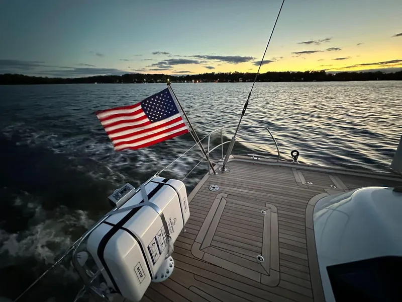Slide: The Image of Hallberg-Rassy 57 yacht deck at sunset, American flag waving, 2023 model. - 47